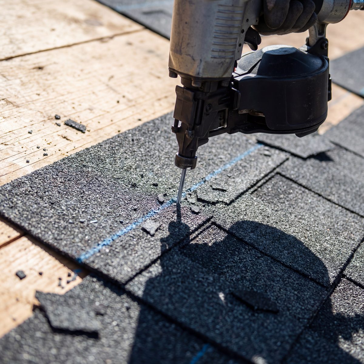 Roofing nail gun driving nail into shingles